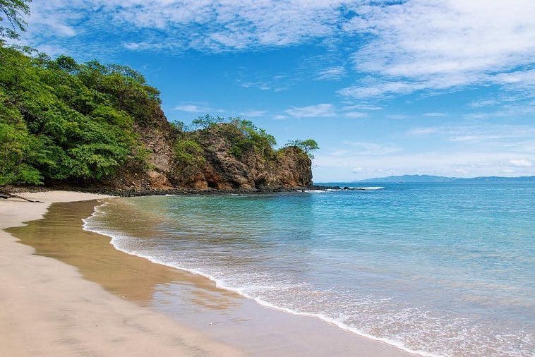 playa penca de arena blanca, aguas turquesas y árboles, al norte de Guanacaste